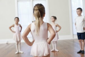 Four children practicing ballet with hands on hips in ballet school